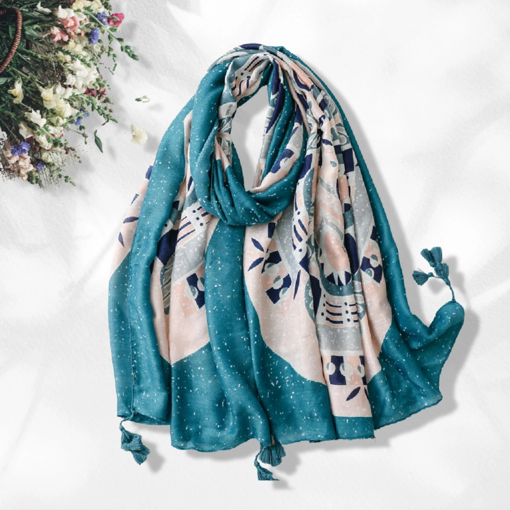 A lightweight scarf with a teal blue base and a beige, gray, and navy abstract botanical pattern, styled on a white background with a decorative floral corner.