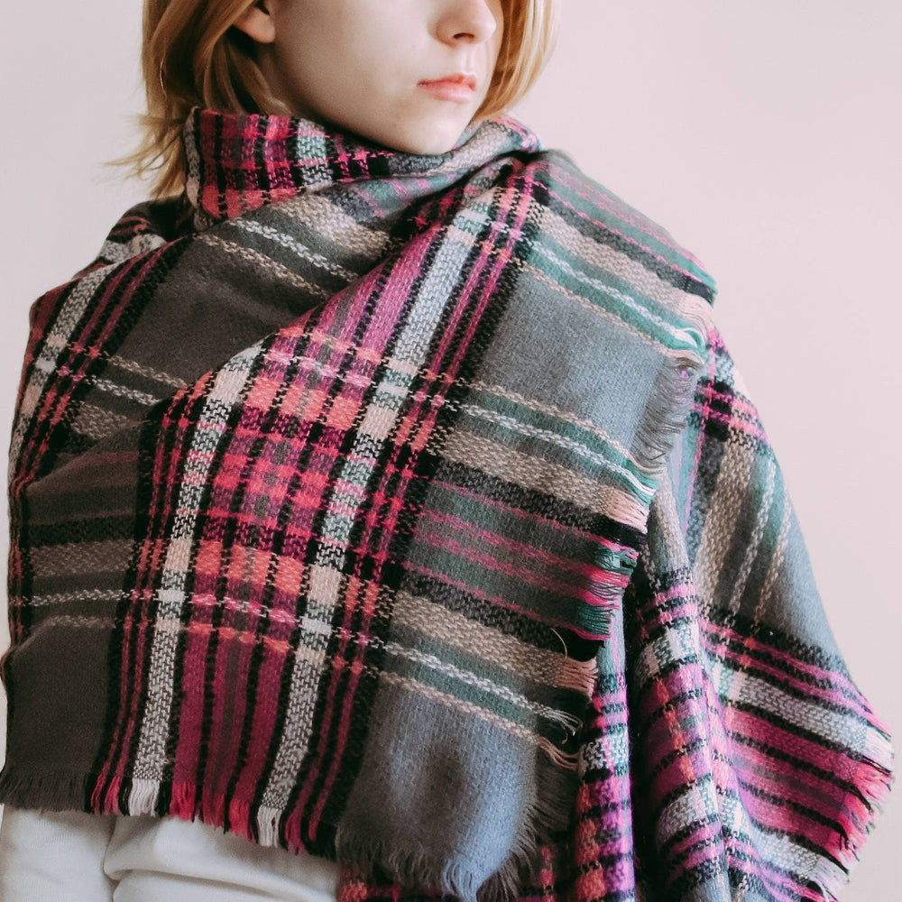 A person wearing a hot pink and gray tartan plaid scarf wrapped around their neck, providing a full view of the scarf's pattern and the way it is worn.