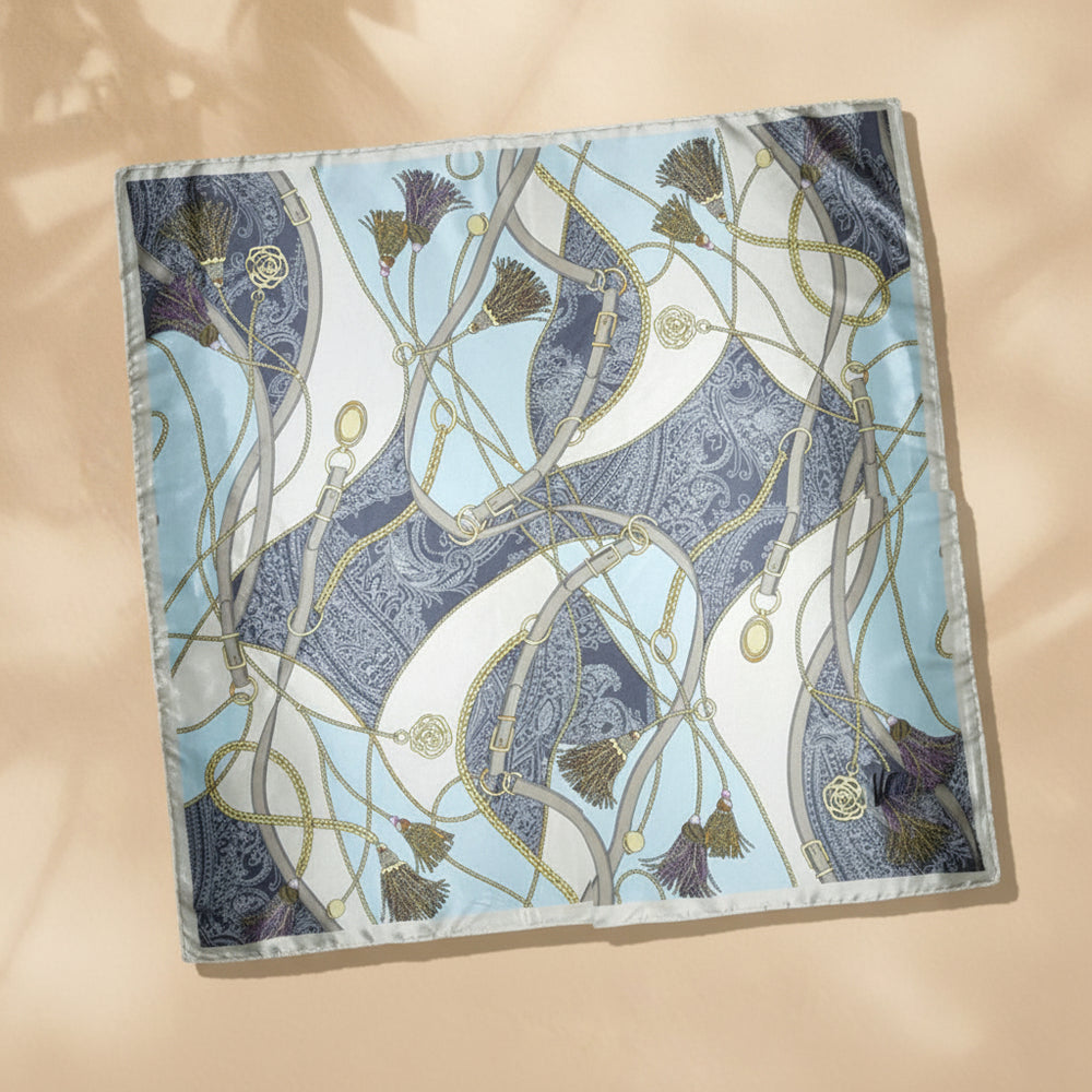 A large satin scarf with a geometric pattern in shades of blue and gold, displayed on a neutral background.