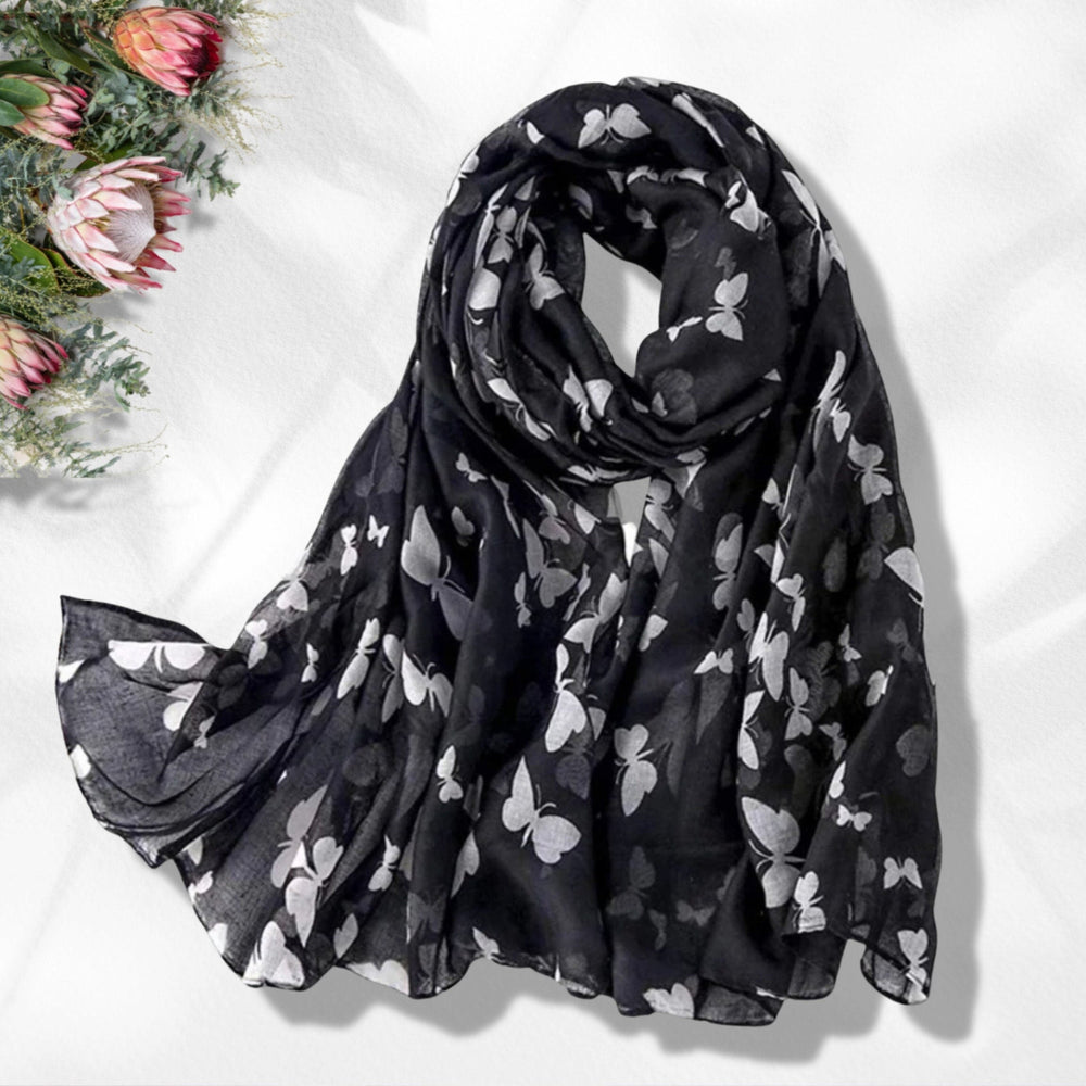 A black scarf with a butterflies print, draped and displayed on a neutral background.