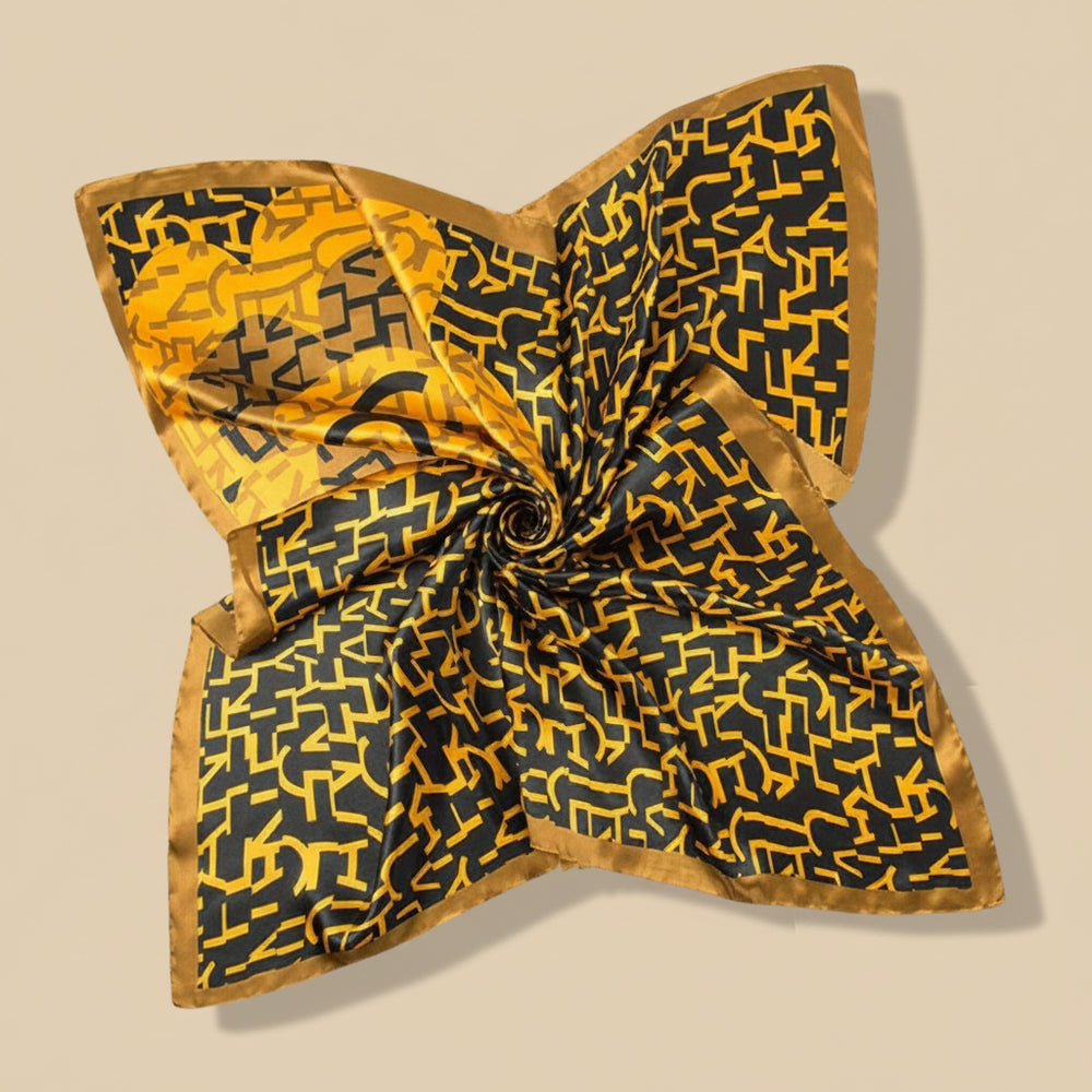 A large satin scarf in mustard color with a geometric pattern, displayed in a draped fashion.