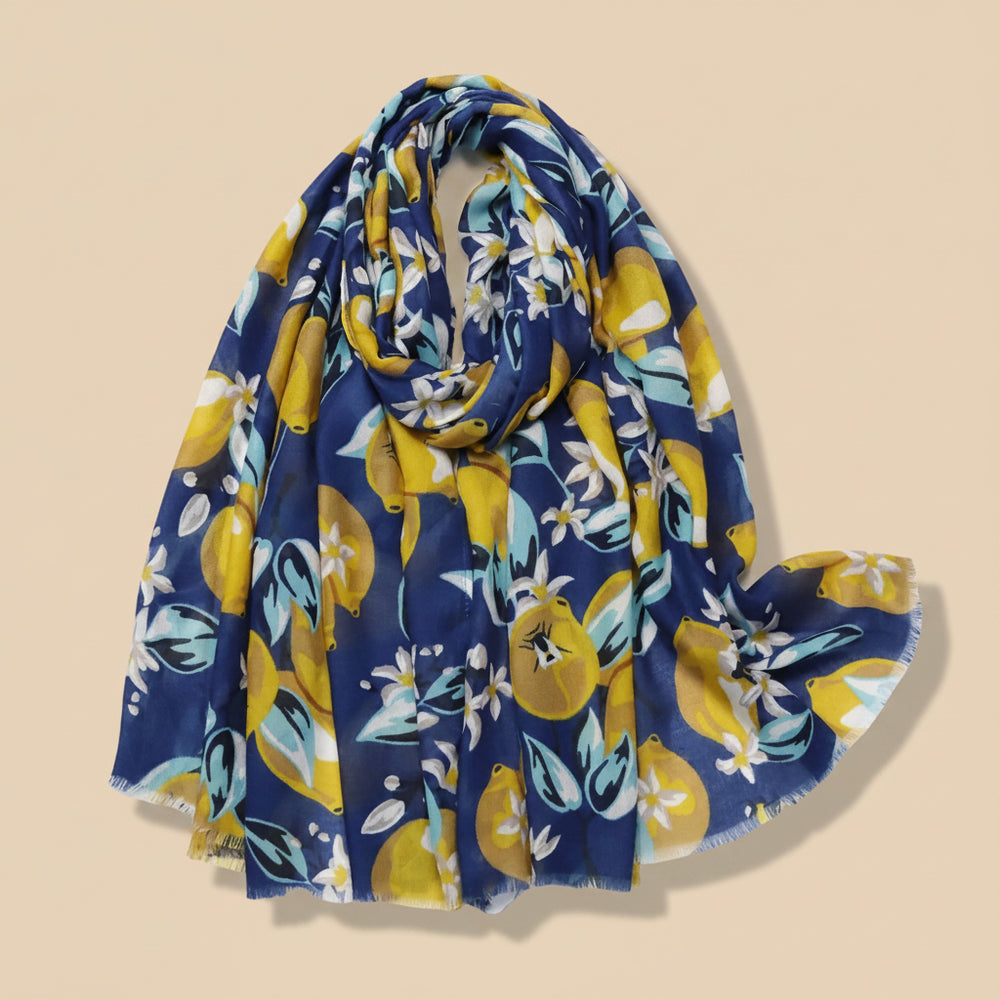 A navy and yellow scarf with a floral lemon print, draped and displayed on a white background with flowers at the bottom edge.